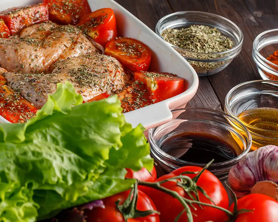 chicken and tomatoes in a roasting pan that has been marinated in stevie's italian dressing and marinade